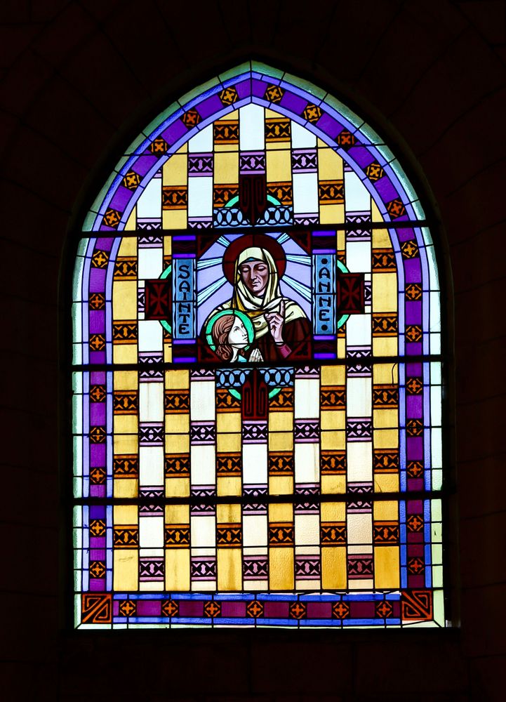 Un vitrail coloré représentant Sainte Anne s'adressant à une jeune femme